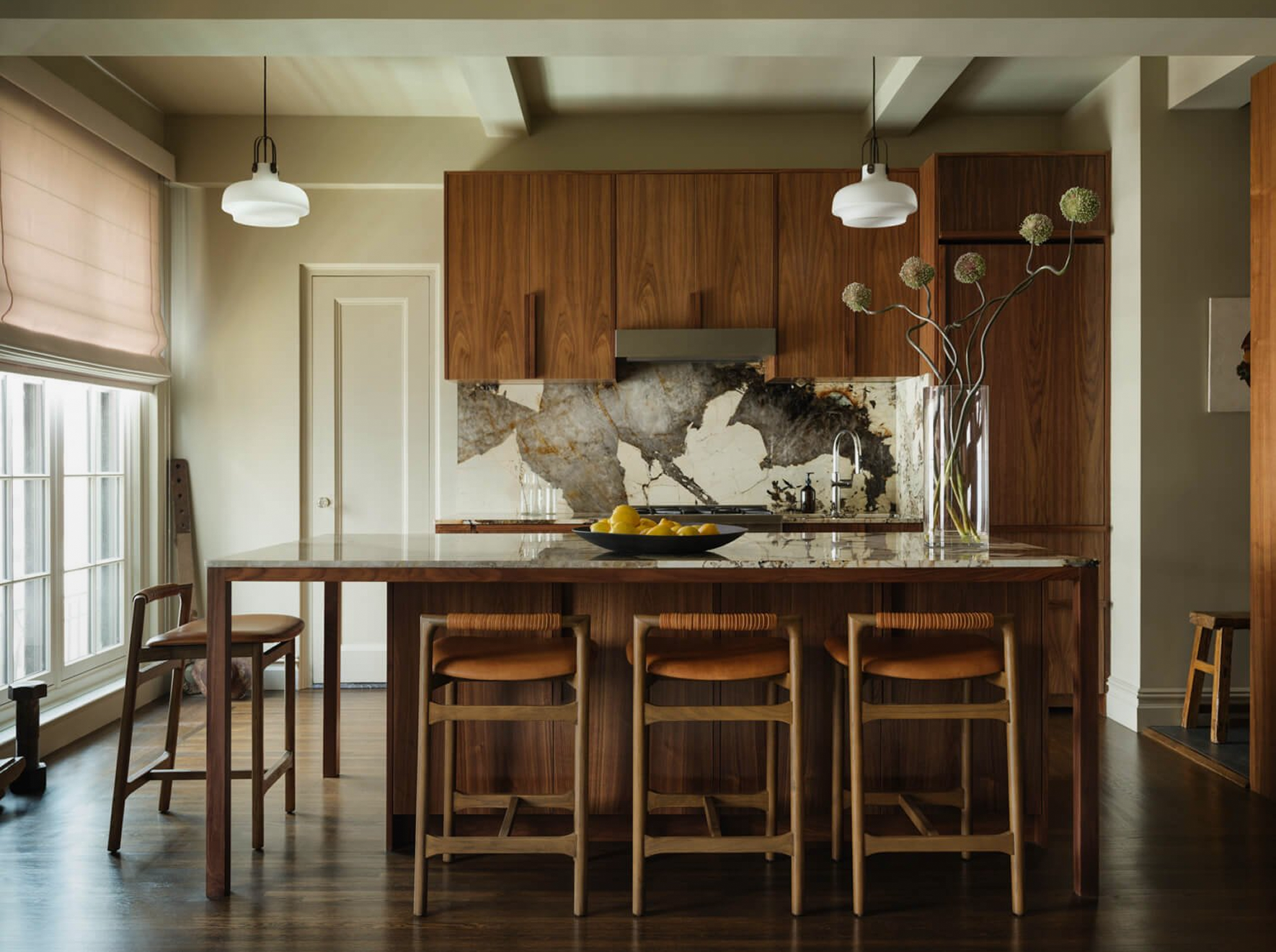 Walnut kitchen with a marble island and leather bar stools in a Mammoth-renovated NYC home