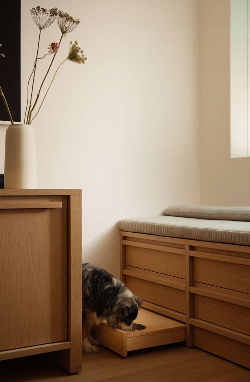 Oak storage bench with a built-in pull-out dog-bowl drawer and a small dog feeding
