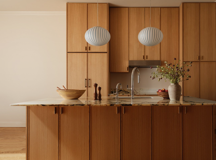 Oak kitchen with a marble-topped island and two ribbed globe pendant lights