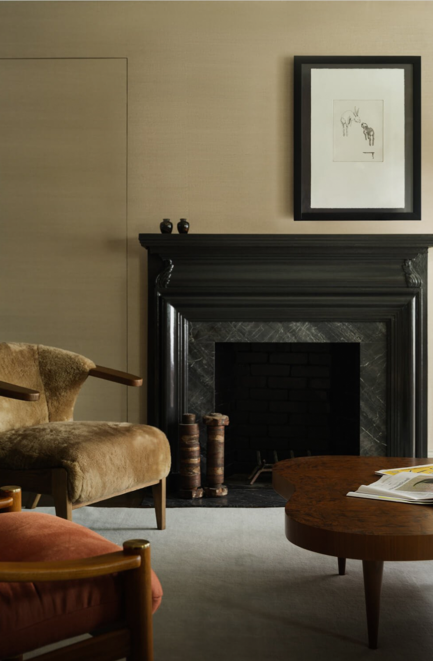Living room with a black marble fireplace, a tan shearling armchair and a burl-wood coffee table