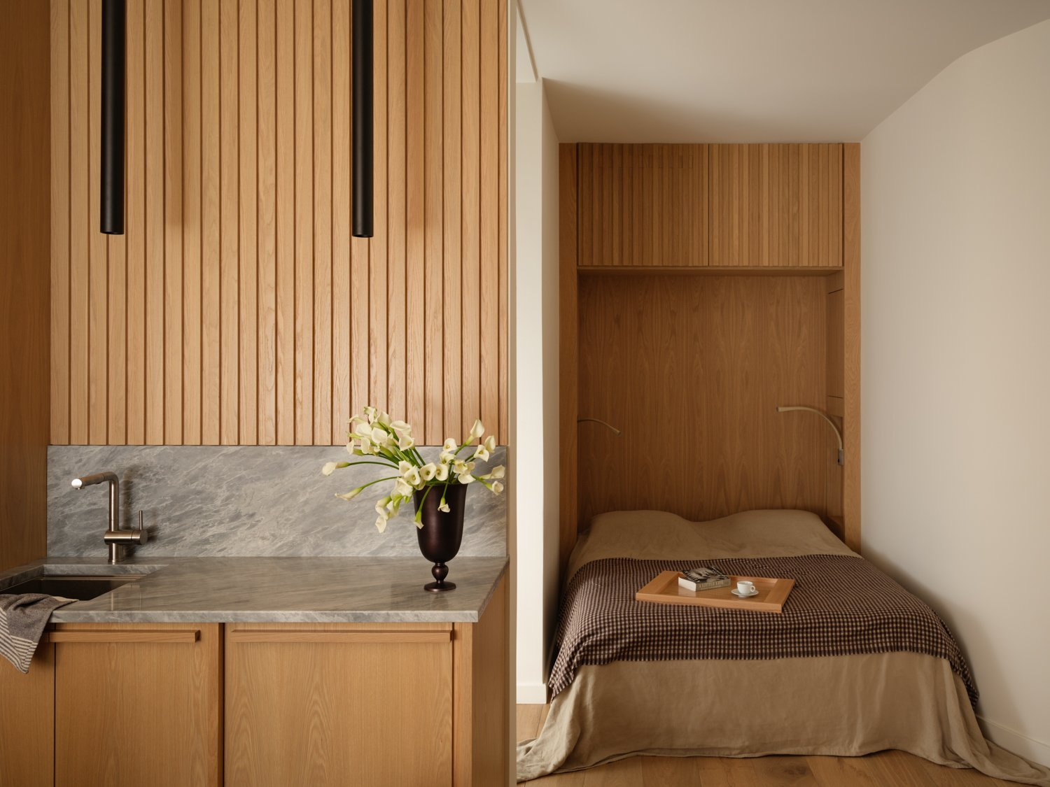 Oak-panelled kitchenette with a marble counter beside a built-in Murphy bed