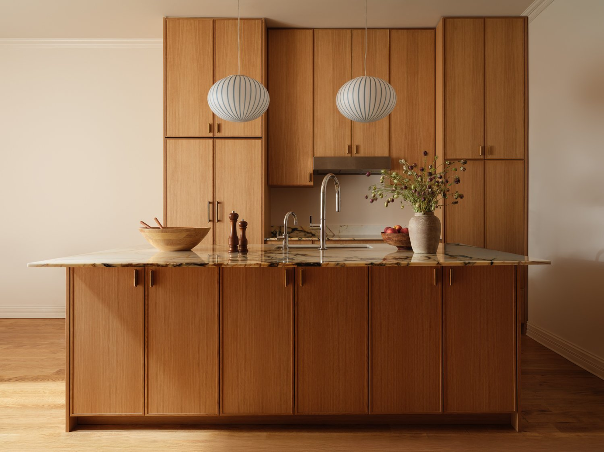 Oak kitchen with a marble-topped island and two ribbed globe pendant lights