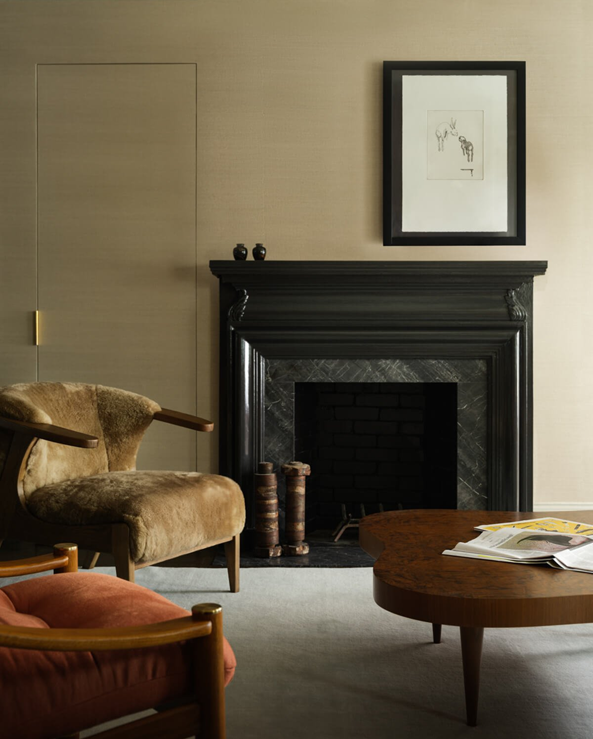 Living room with a black marble fireplace, a tan shearling armchair and a burnt-orange velvet chair