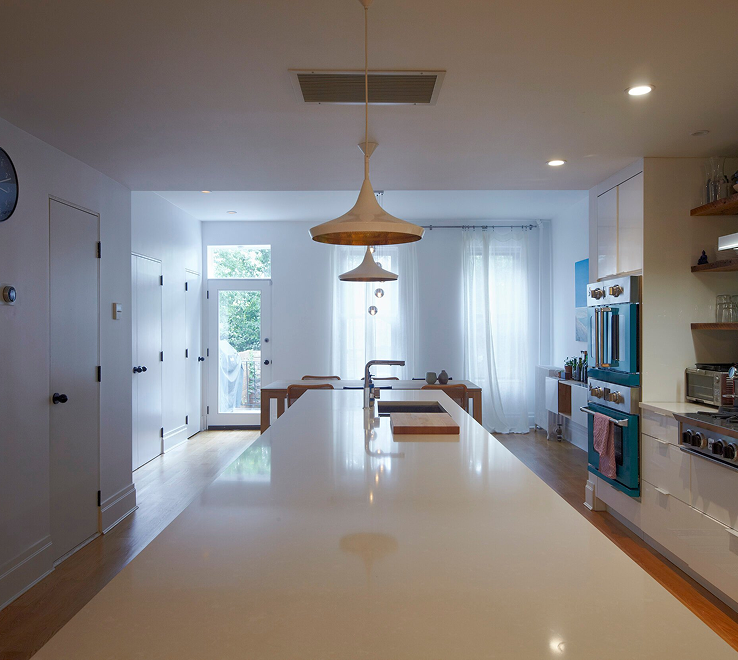 White townhouse kitchen with a long island, wood pendants and teal ovens — Brooklyn townhouse renovation