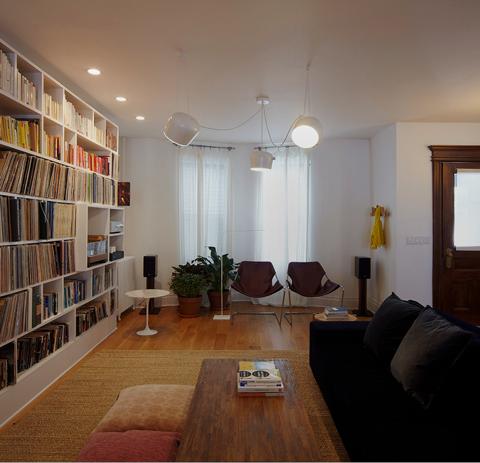 Library den with floor-to-ceiling bookshelves, a record collection and a black sofa