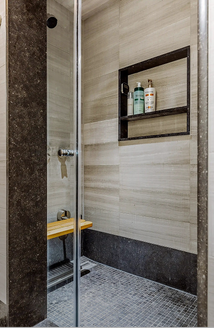 Tiled steam shower with a teak bench and a glass door