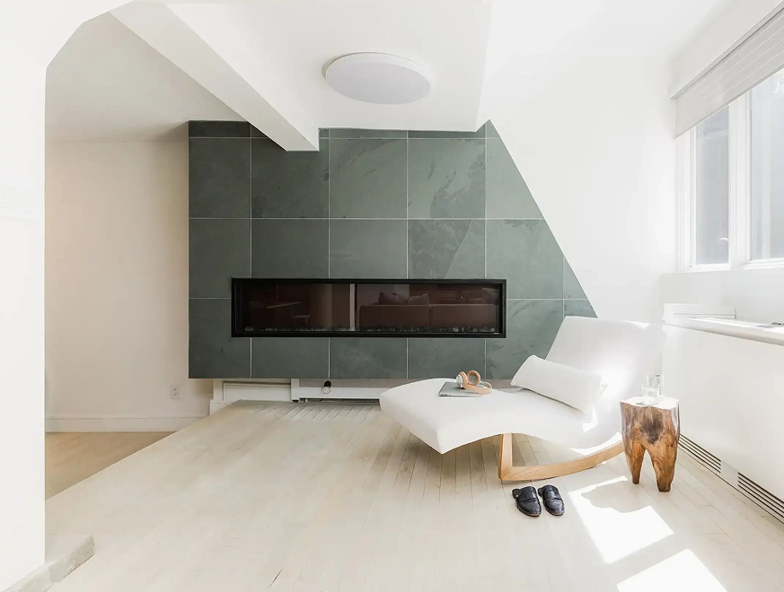 Room with a green-tiled fireplace and a white chaise lounge